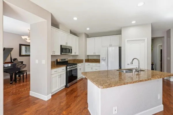 a kitchen with stainless steel appliances granite countertop a refrigerator a stove top oven and a sink