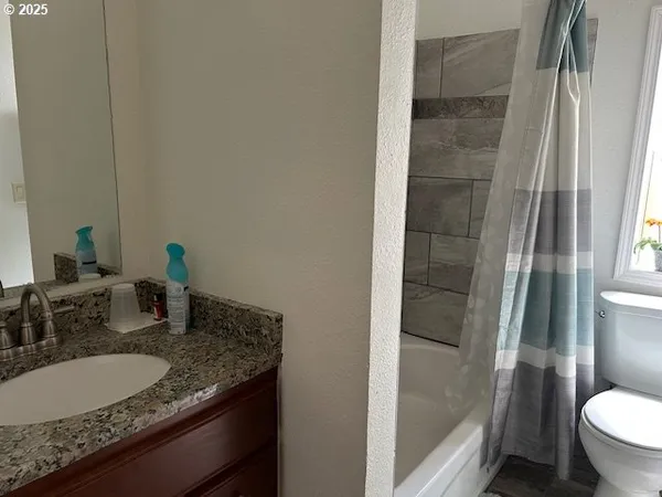 a bathroom with a granite countertop sink and a mirror with toilet