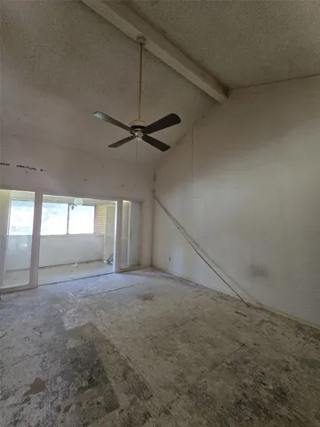 en empty room with windows and ceiling fan