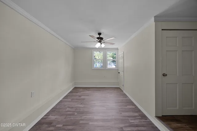 a view of an empty room with window and hardwood floor