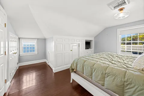 a bed sitting in a spacious bedroom next to a window and a flat screen tv