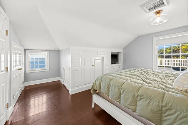 a bed sitting in a spacious bedroom next to a window and a flat screen tv