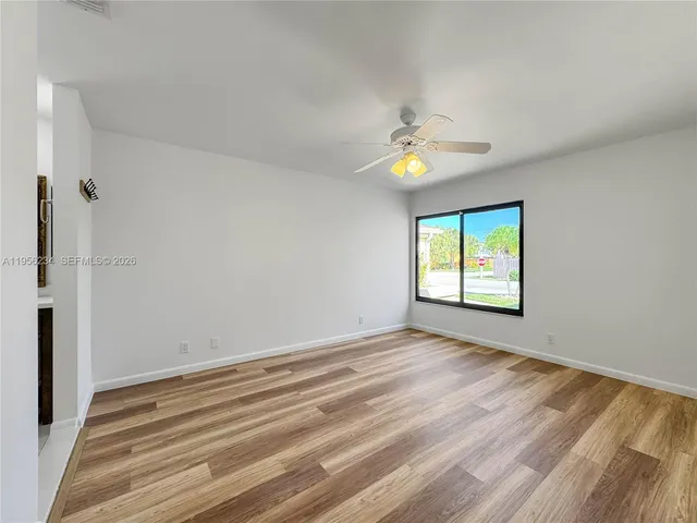 a view of an empty room with window and chandelier fan