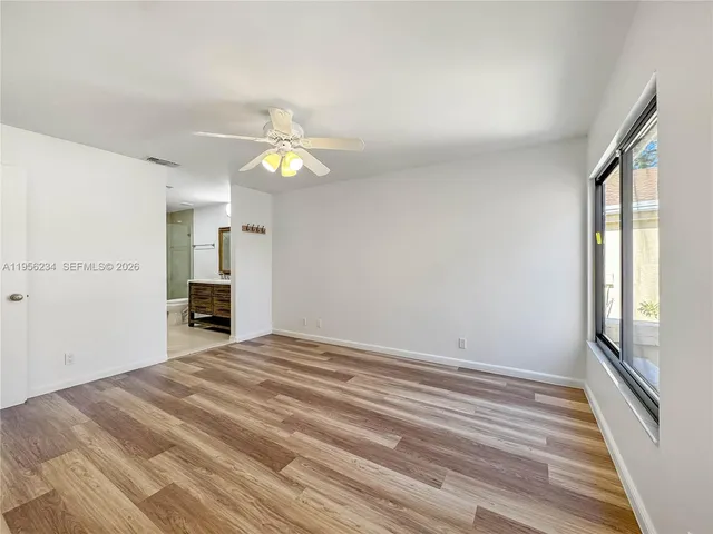 a view of an empty room with window and chandelier fan