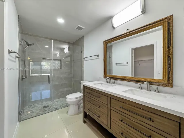 a bathroom with a sink a toilet a mirror and shower