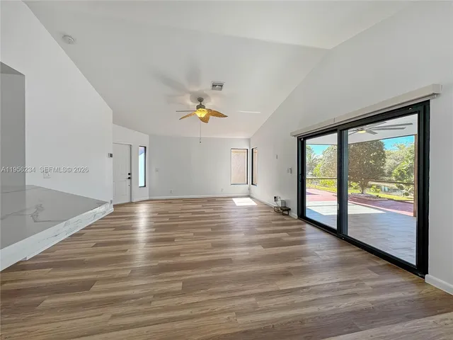 a view of an empty room with a window and wooden floor