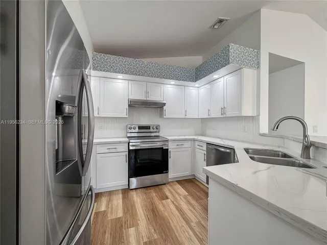 a kitchen with a sink cabinets stainless steel appliances and a window