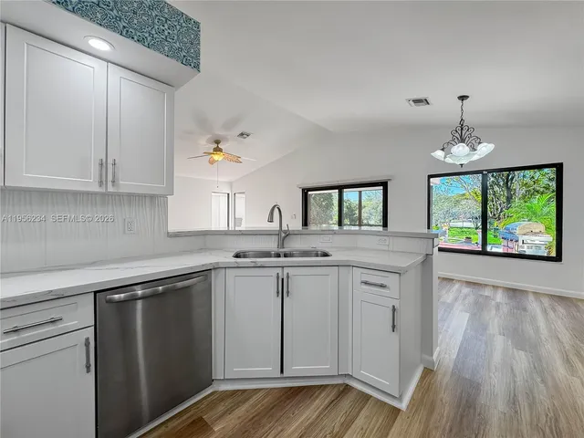 a kitchen with kitchen island granite countertop a sink window and cabinets