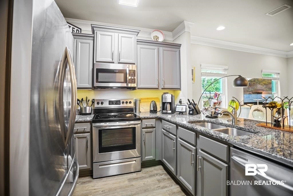 25806 Pollard Road, Unit 27 Daphne, AL 36526 - Photo 19 of 46 Kitchen with stainless steel appliances, dark stone countertops, gray cabinets, crown molding, and light wood finished floors