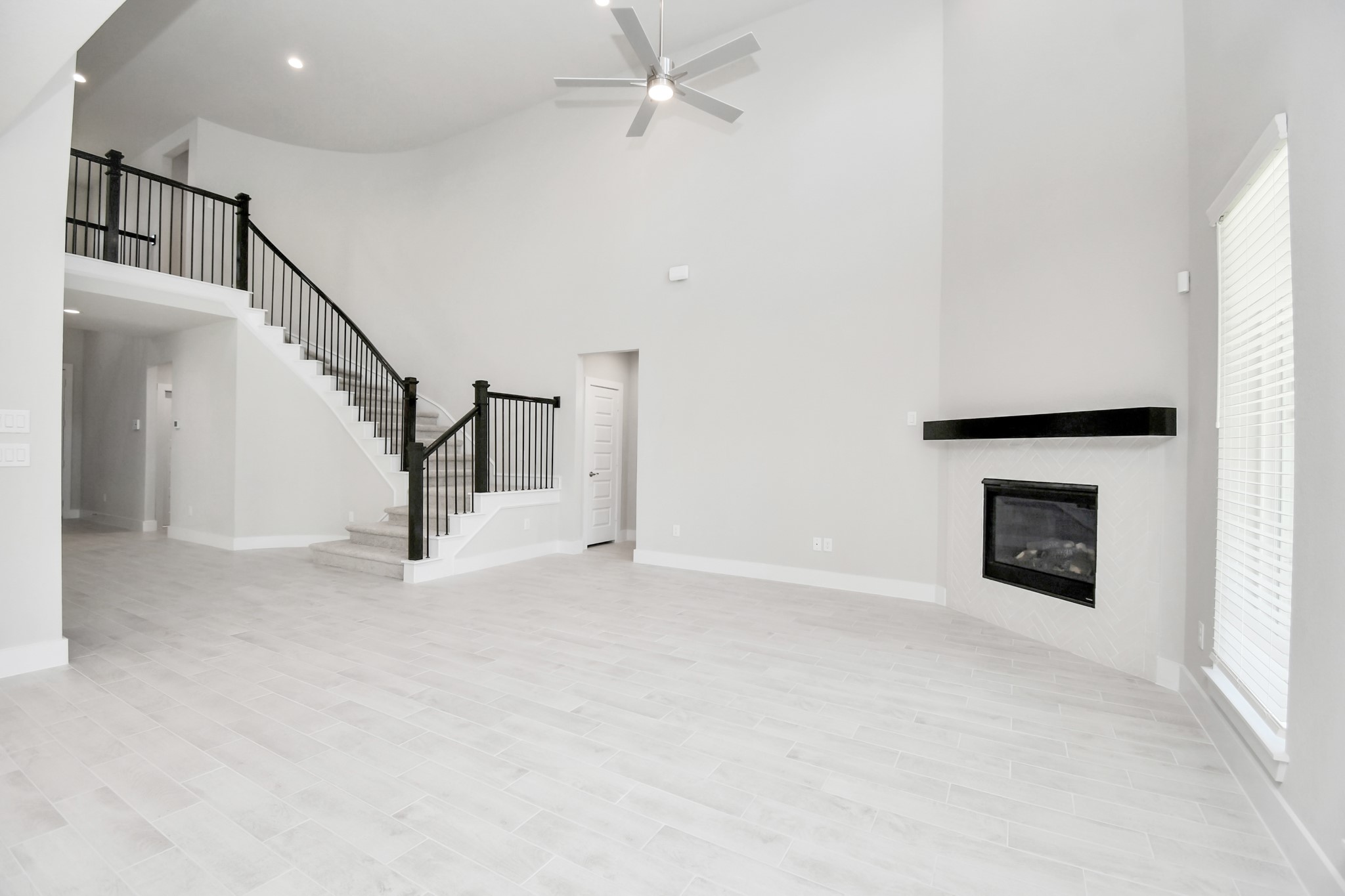 3038 Native Spg Drive Spring, TX 77373 - Photo 18 of 40 Relax and unwind in this inviting family room, illuminated by abundant natural light streaming in through tall windows, complemented by high ceilings and stunning flooring. Stay comfortable year-round with the gentle breeze from the ceiling fan, creating the perfect atmosphere for family gatherings. Sample photo of completed home with similar floor plan. Actual colors and selections may vary.