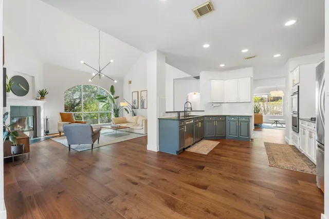 a kitchen with stainless steel appliances granite countertop a stove a sink and white cabinets with wooden floor