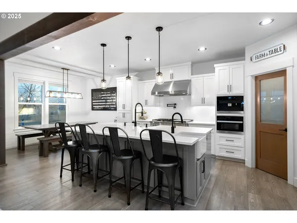 a open kitchen with stainless steel appliances kitchen island granite countertop a table chairs and a refrigerator