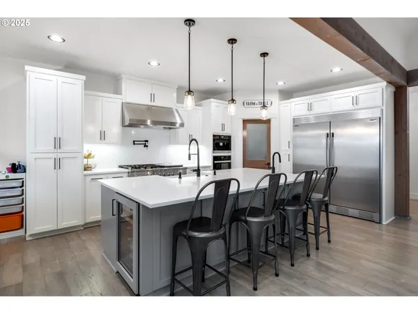 a kitchen with stainless steel appliances kitchen island granite countertop a table chairs and a refrigerator