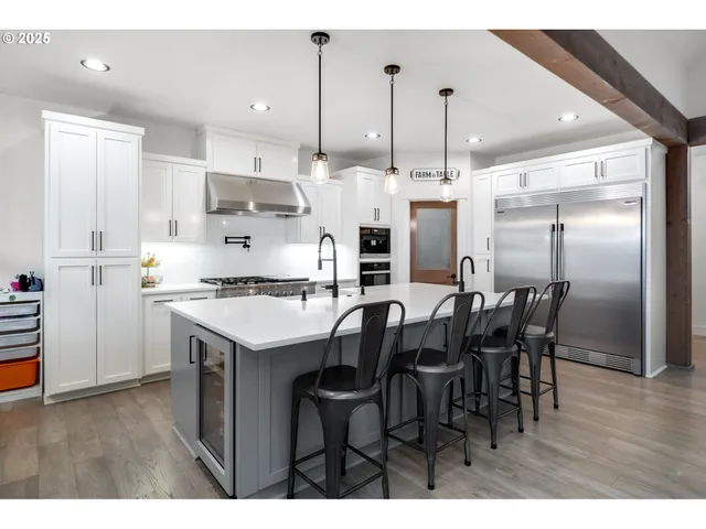 a kitchen with stainless steel appliances kitchen island granite countertop a table chairs and a refrigerator