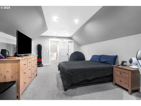 a spacious bedroom with a bed and a flat tv screen on dresser