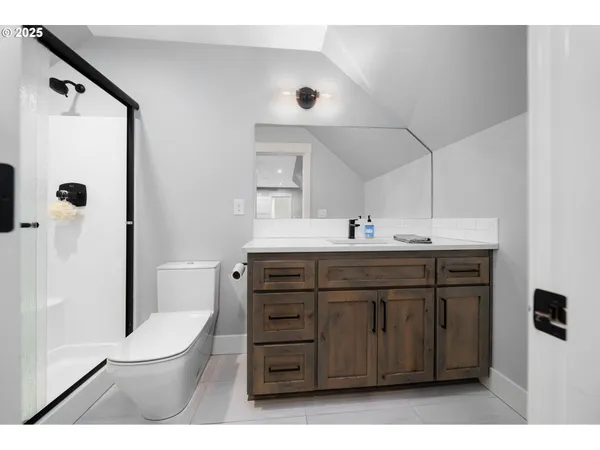 a bathroom with a sink a toilet a mirror and shower