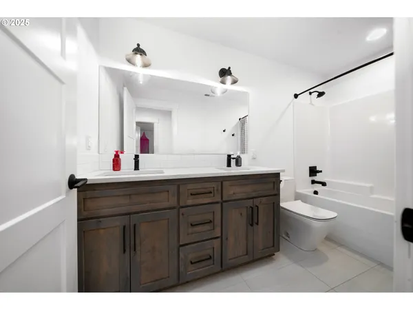 a bathroom with a double vanity sink toilet mirror and bathtub