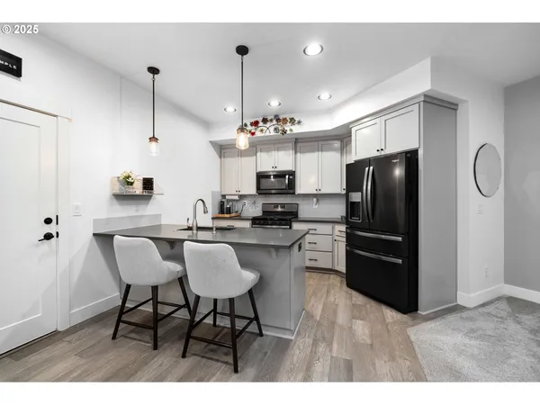 a kitchen with stainless steel appliances kitchen island granite countertop a refrigerator a stove a microwave a dining table and chairs