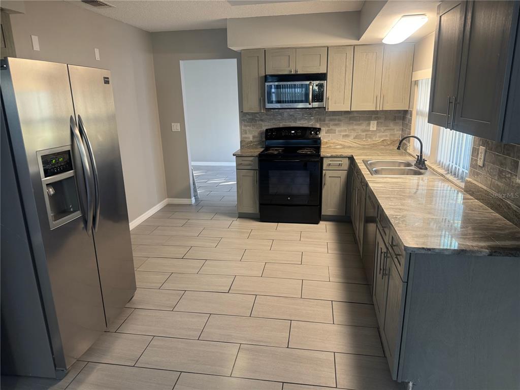 13016 Sirius Lane Hudson, FL 34667 - Photo 2 of 13 a kitchen with stainless steel appliances granite countertop a refrigerator a stove a sink a microwave and a refrigerator