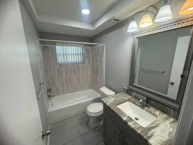 a bathroom with a granite countertop sink toilet a mirror and shower