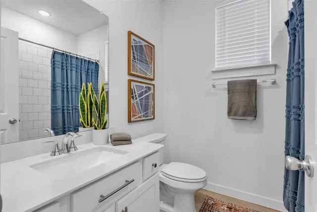 a bathroom with a granite countertop sink a toilet and mirror