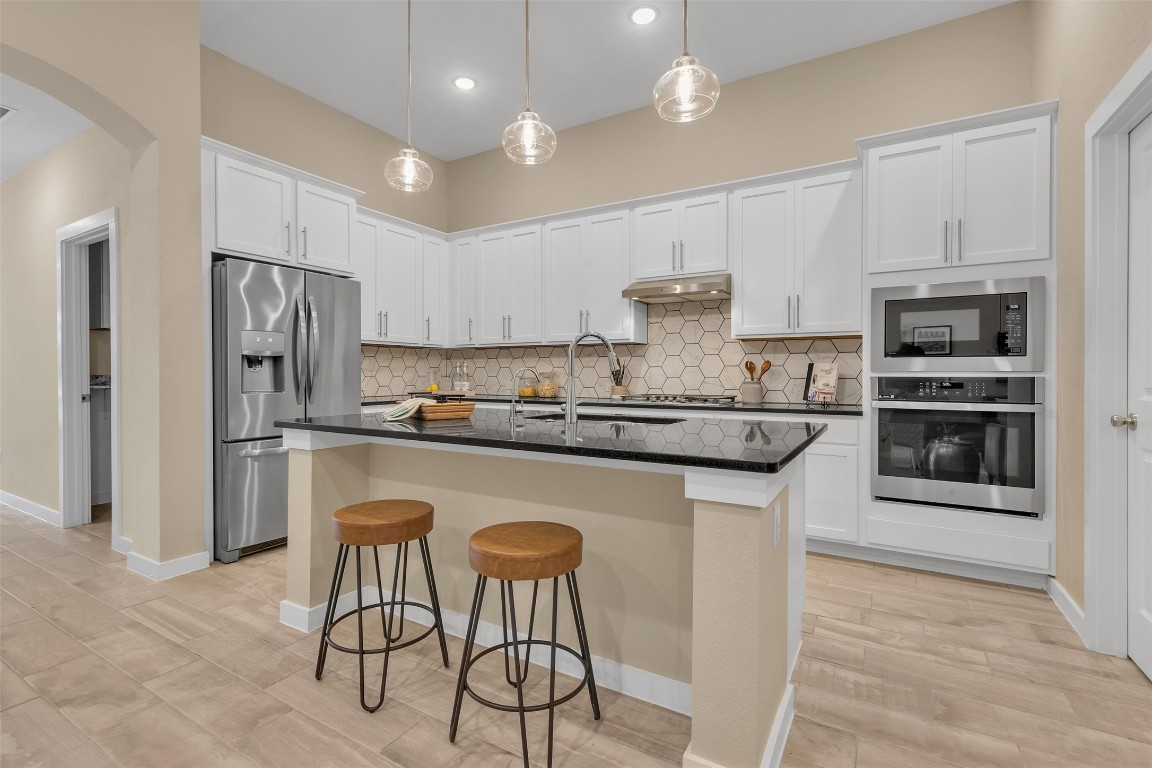 153 Billowing Way Kyle, TX 78640 - Photo 10 of 22 a kitchen with stainless steel appliances granite countertop a stove a refrigerator a sink a dining table and chairs with wooden floor