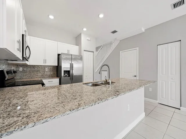 a kitchen with stainless steel appliances granite countertop a sink and a refrigerator