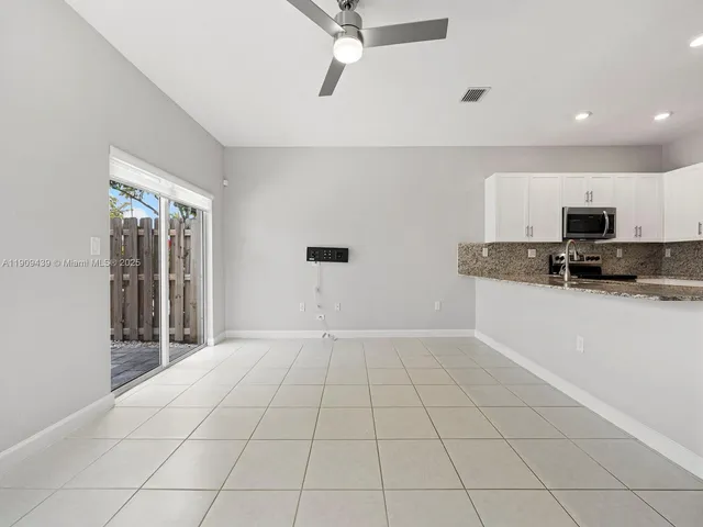 a view of a kitchen with a sink and dishwasher a refrigerator with white cabinets