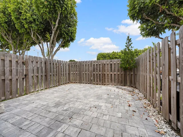 a view of backyard with wooden fence and trees
