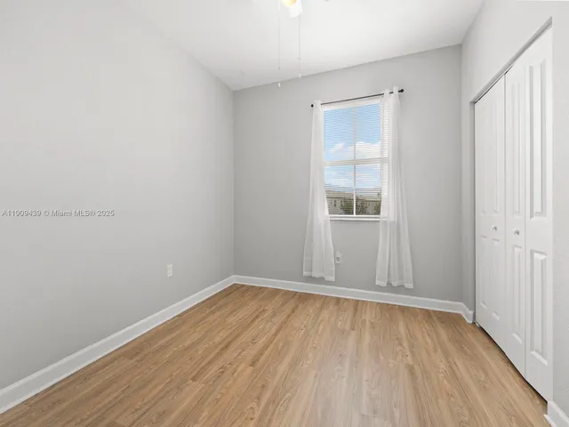 an empty room with wooden floor & closet area
