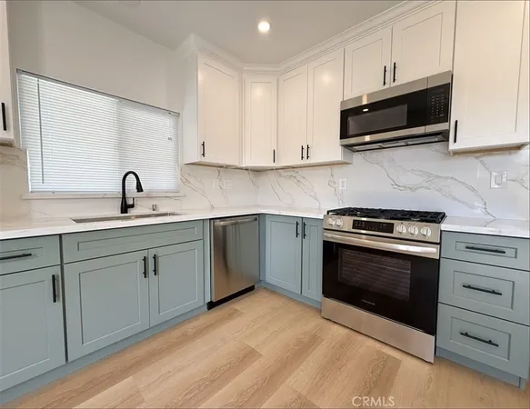 a kitchen with stainless steel appliances granite countertop a sink dishwasher a stove and a microwave oven with cabinets