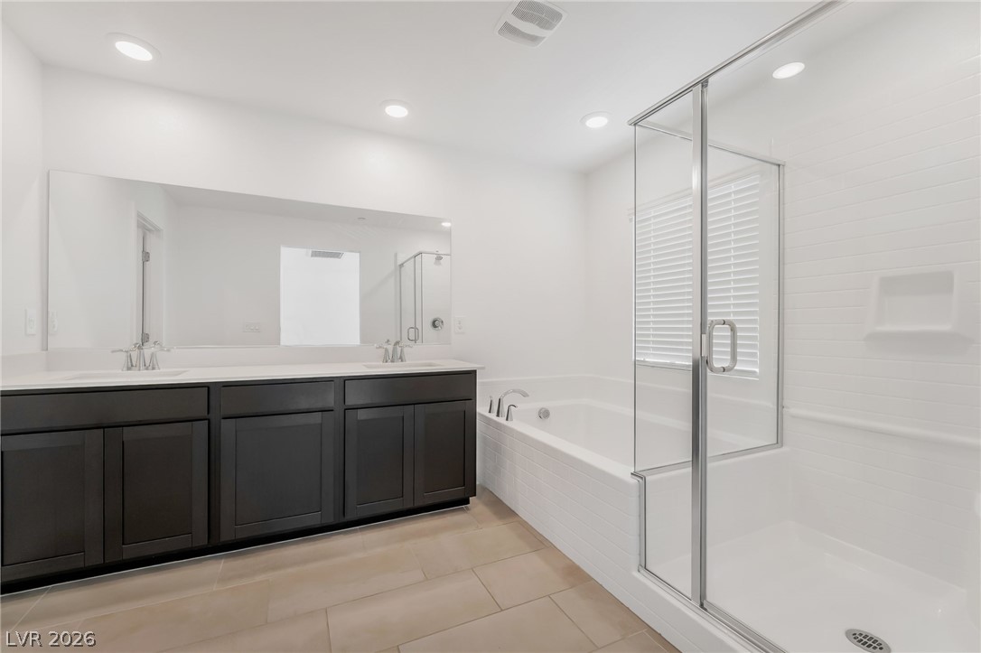 894 Cadence View Way Henderson, NV 89011 - Photo 16 of 23 Indulge in a primary bathroom featuring a spacious dual vanity, a soaking tub, and a separate glass-enclosed shower.
