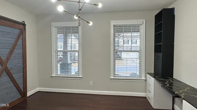 a open kitchen with stainless steel appliances granite countertop a refrigerator a sink dishwasher and a dining table with wooden floor