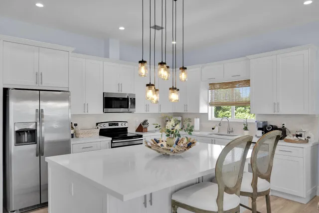 a kitchen with stainless steel appliances a microwave a stove a refrigerator a sink a dining table and chairs with wooden floor