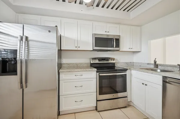 a kitchen with stainless steel appliances granite countertop white cabinets and refrigerator