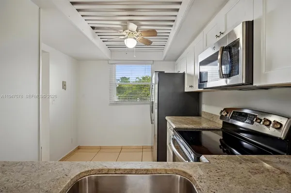 a kitchen with stainless steel appliances granite countertop a refrigerator a stove and a sink with wooden cabinets