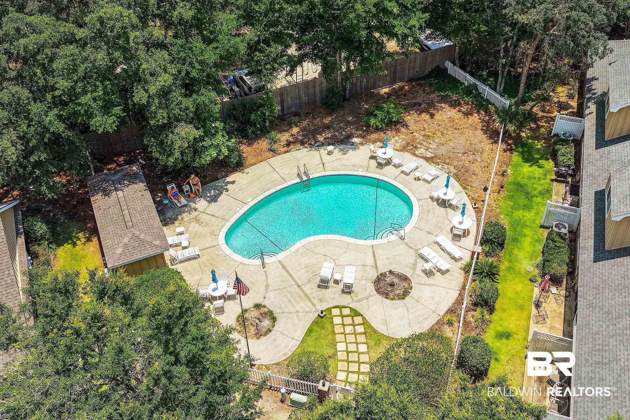 430 West Fort Morgan Road, Unit 704 Gulf Shores, AL 36542 - Photo 30 of 35 Freestyle swimming pool with surrounding concrete patio, bordered by mature trees and manicured lawn areas