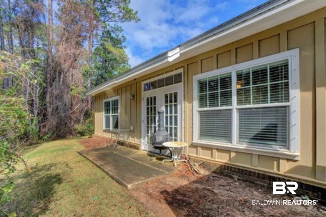 430 West Fort Morgan Road Gulf Shores, AL 36542 - Photo 25 of 27 Exterior patio featuring a concrete slab, board and batten siding, white-framed windows, and white French doors