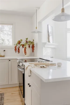 a white kitchen with wooden cabinets a sink a stove and a window
