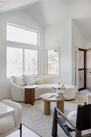 a living room with kitchen island furniture a table and large windows