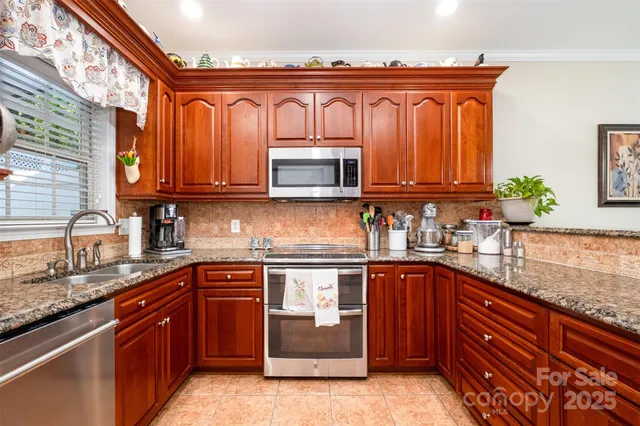 a kitchen with stainless steel appliances granite countertop wooden cabinets a stove top oven a sink and dishwasher