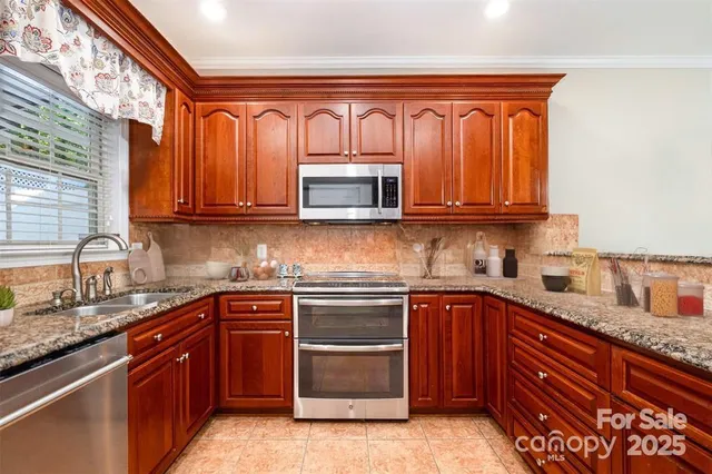 a kitchen with stainless steel appliances granite countertop wooden cabinets and a stove top oven