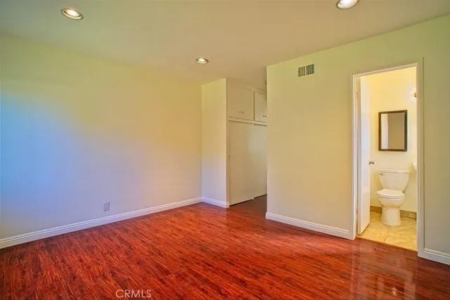 a view of an empty room with wooden floor and a bathroom