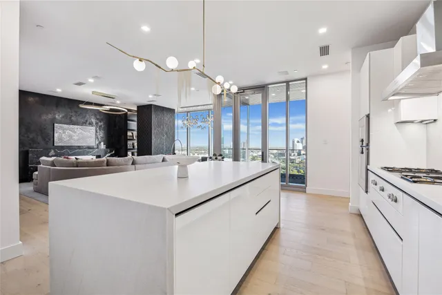 a kitchen with stainless steel appliances kitchen island granite countertop a sink and a stove top oven with wooden floor