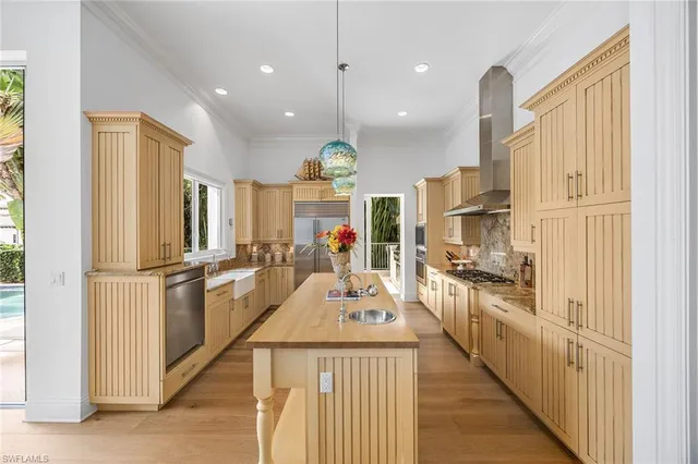 a kitchen with stainless steel appliances kitchen island granite countertop a refrigerator a stove a sink dishwasher and white cabinets with wooden floor