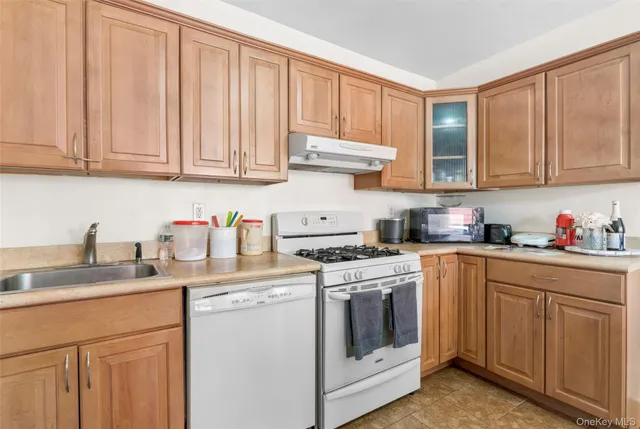a kitchen with granite countertop stainless steel appliances white cabinets sink and a dishwasher