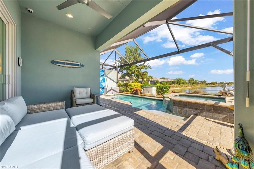 5756 Elbow Avenue Naples, FL 34113 - Photo 28 of 45 View of patio / terrace with a sunroom, glass enclosure, a ceiling fan, a pool with connected hot tub, and a water view