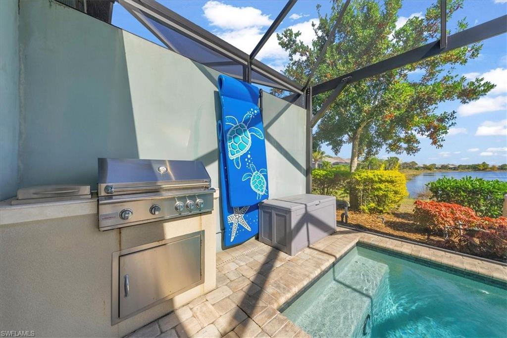 5756 Elbow Avenue Naples, FL 34113 - Photo 30 of 45 View of swimming pool featuring a lanai, exterior kitchen, a patio, a water view, and a swimming pool