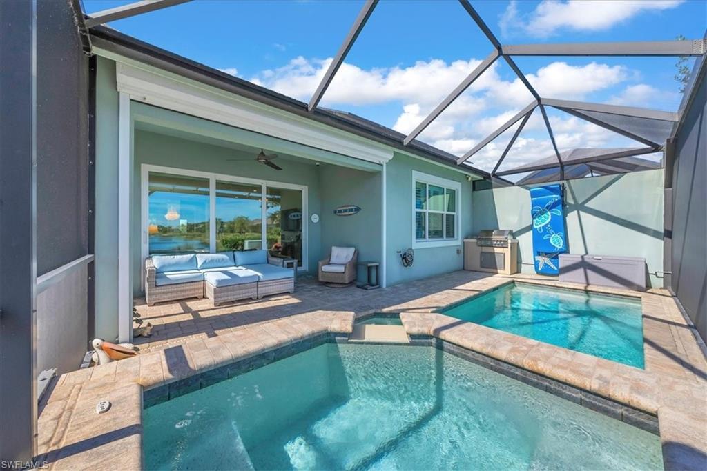5756 Elbow Avenue Naples, FL 34113 - Photo 5 of 45 View of swimming pool with a sunroom, a patio area, glass enclosure, a pool with connected hot tub, and a grill