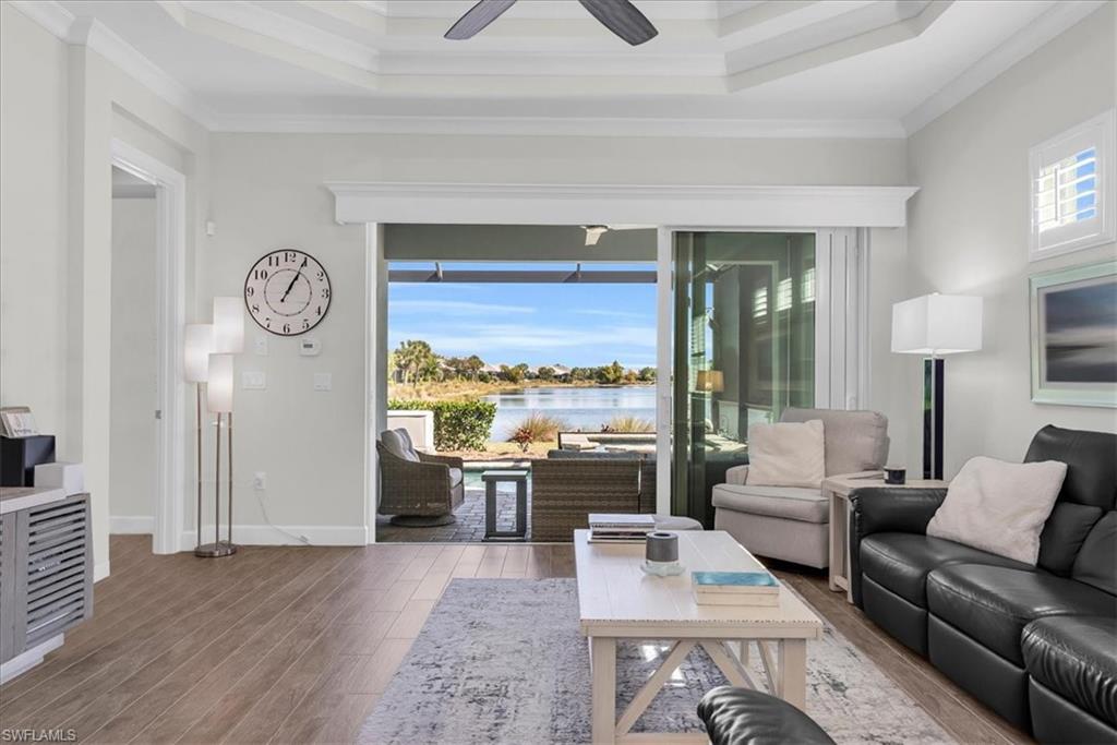 5756 Elbow Avenue Naples, FL 34113 - Photo 9 of 45 Living area featuring crown molding, wood finished floors, a tray ceiling, a water view, and a ceiling fan